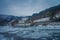 Outdoor view of frozen river with some wooden houses at one side of the road at Gol Mountain Are