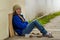 Outdoor view of homeless smiling woman begging on the street in cold autumn weather sitting on the floor at sidewalk