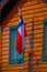 Outdoor view of wooden building with a Chilean flag waving in Chiloe island in a gorgeous blue sky in Chile