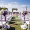 Outdoor wedding ceremony setup with white chairs and floral decorations