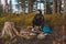 Outdoor wilderness trekking enthusiast sitting by a campfire enjoying breakfast at sunrise. Breakfast and catching vitamin D at