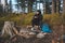 Outdoor wilderness trekking enthusiast sitting by a campfire enjoying breakfast at sunrise. Breakfast and catching vitamin D at