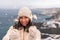 Outdoor winter portrait of elegant happy smiling beige hat, light faux fur coat holding heart sparkler, posing against