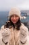 Outdoor winter portrait of elegant happy smiling beige hat, light faux fur coat holding heart sparkler, posing against