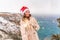 Outdoor winter portrait of happy smiling woman, light faux fur coat holding heart sparkler, posing against sea and snow