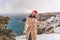 Outdoor winter portrait of happy smiling woman, light faux fur coat holding heart sparkler, posing against sea and snow