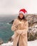 Outdoor winter portrait of happy smiling woman, light faux fur coat holding heart sparkler, posing against sea and snow