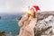 Outdoor winter portrait of happy smiling woman, light faux fur coat holding heart sparkler, posing against sea and snow