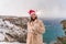 Outdoor winter portrait of happy smiling woman, light faux fur coat holding heart sparkler, posing against sea and snow