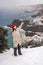 Outdoor winter portrait of happy smiling woman, light faux fur coat holding heart sparkler, posing against sea and snow