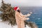 Outdoor winter portrait of happy smiling woman, light faux fur coat holding heart sparkler, posing against sea and snow