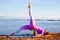 Outdoor yoga practice. Attractive woman practicing variation of Setu Bandhasana, Shoulder supported bridge pose with one leg up.