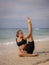 Outdoor yoga practice near the ocean. Attractive Caucasian woman practicing Eka Pada Sirsasana, Foot-behind-the-Head Pose.