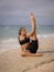 Outdoor yoga practice near the ocean. Attractive Caucasian woman practicing Eka Pada Sirsasana, Foot-behind-the-Head Pose.