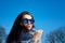 Outdoors closeup portrait of beautiful young woman with mirrored sunglasses over blue sky during early spring time in