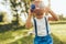 Outdoors closeup portrait of little boy playing with a binoculars searching for an imagination or exploration in summer day in