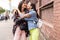 Outdoors fashion portrait young pretty best girls friends in friendly hug. Walking at the city.