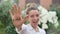 Outdoors female portrait of young adult woman in white shirt showing her hand with slogan `I voted` on flowers