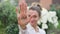 Outdoors female portrait of young adult woman in white shirt showing her hand with slogan 'I voted' on flowers