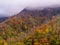 Outdoors hiking view with low sweeping clouds over the Chimney Top mountain with beautiful saturated fall colors in the Great Smok