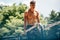 Outdoors image of young fitness muscular man doing exercises on horizontal crossbar at sportsground. Handsome athletic shirtless