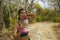 Outdoors lifestyle portrait of young attractive tired and thirsty Asian woman drinking water after hard running workout cooling