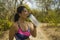 Outdoors lifestyle portrait of young attractive tired and thirsty Asian woman drinking water after hard running workout cooling