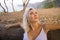 Outdoors lifestyle portrait of young beautiful and relaxed blond woman leaning on tree trunk enjoying peaceful nature surrounded