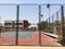 Outdoors mini football and basketball court with ball gate and basket surrounded with high protective fence.