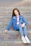 Outdoors portrait of adorable smiling little girl child sitting on the steps of the stairs