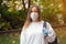 Outdoors portrait of beautiful young woman wearing cotton white mask and medicalgloves greeting and say hello, Nature and trees in