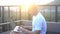 Outdoors portrait of handsome young man working on a laptop computer while sitting on a rooftop over beautiful sunrise