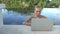 Outdoors portrait of pretty blonde happy woman in bikini with laptop computer in a rooftop infinity swimming pool