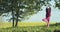 Outdoors portrait of woman standing in tree position vrikshasana on nature background. Sportive girl in hood doing yoga