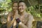 Outdoors portrait of young beautiful and happy couple practicing yoga workout together at tropical forest gazebo smiling cheerful