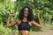 Outdoors portrait of young happy and attractive hispanic woman with curly hair and athletic body gesturing blissful and carefree