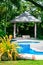 Outdoors relaxing swimming pool with gazebo and tropical garden