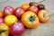 Outdoors still life with ripe red and orange tomatoes on brown wooden table surface as background