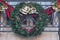 Outdoors Winter Holiday decoration concept: Christmas Wreath with Golden Jingle Bells and Holly Berries decorating