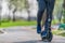 Outdoors workout exercise background of man ridding on kick scooter on pavement in park