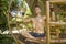Outdoors yoga practice - young happy and attractive man doing yoga workout sitting in lotus position at green forest gazebo