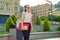 Outdor portrait of female student 16, 17 years old. Girl in glasses, with backpack, textbooks. City background.