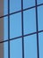 The outer window of the facade of a building, which reflects a cloudless sky