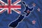 Outline map of New Zealand against the backdrop of a waving textile New Zealand flag. 3D illustration