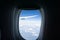 Outlook through plane window while traveling with window surround framing blue sky and clouds with focus on wing outside.