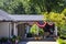 Outside covered patio with furniture and patriotic Forth of July bunting and American flags stuck in flower bed and pots