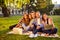 Outside photo of happy diverse five girlfriends and boyfriends sitting on blanket and hugging