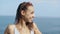 Outside portrait of beautiful young sexy woman in white bikini standing on bay at seaside, against a blue sea.