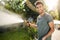 Outside portrait of young attractive caucasian gardener with beard and stylish hairstyle in blue t-shirt smiling in