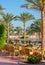 Outside seating terrace, patio area, in the sun, blue sky and palm trees.